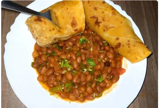 Freshly made Kenyan chapati stacked on a plate, served with beef stew and vegetables.